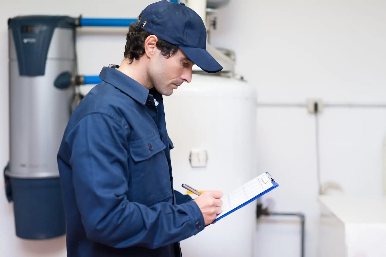 A plumber with a clipboard checking a list to ensure proper water heater repair